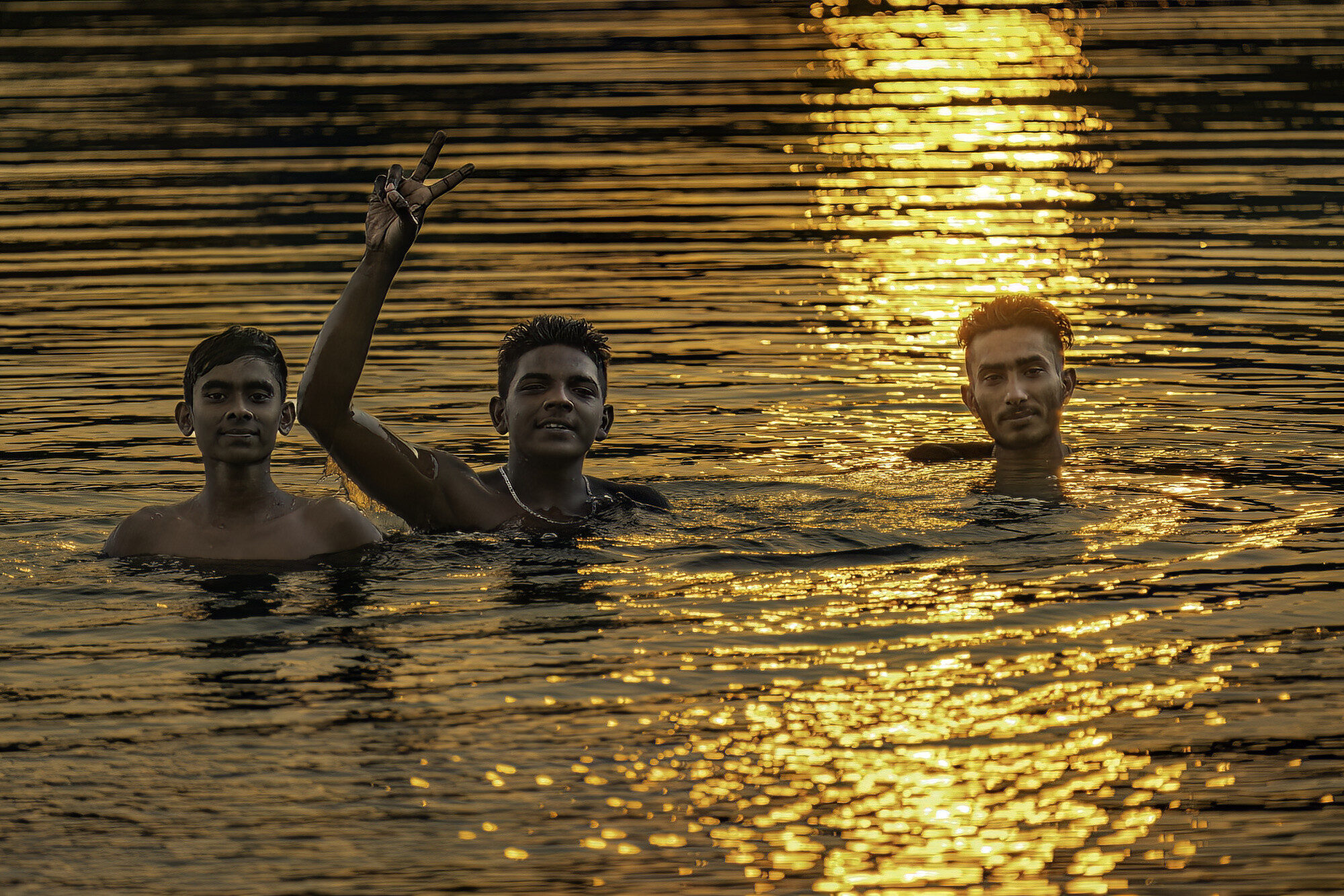 Three Sri Lankan village boys bath in a lake